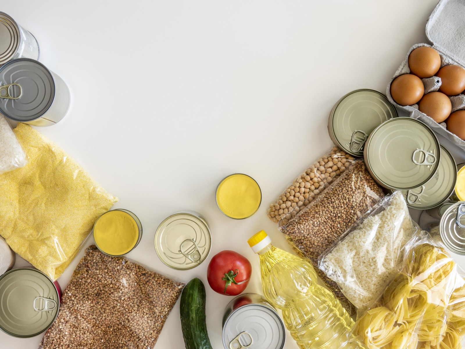 Ingredientes, granos y alimentos enlatados sobre una mesa blanca